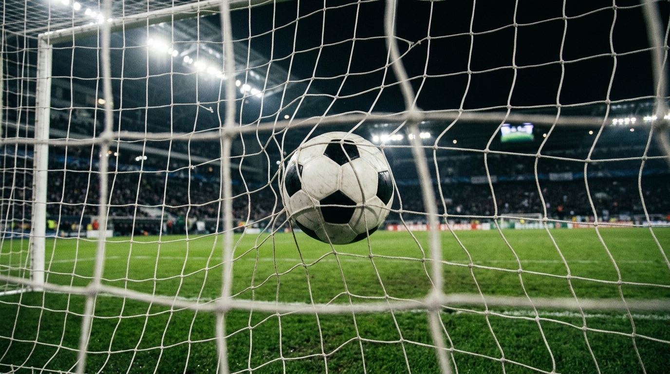 Balón entrando a la red de una portería en un estadio iluminado