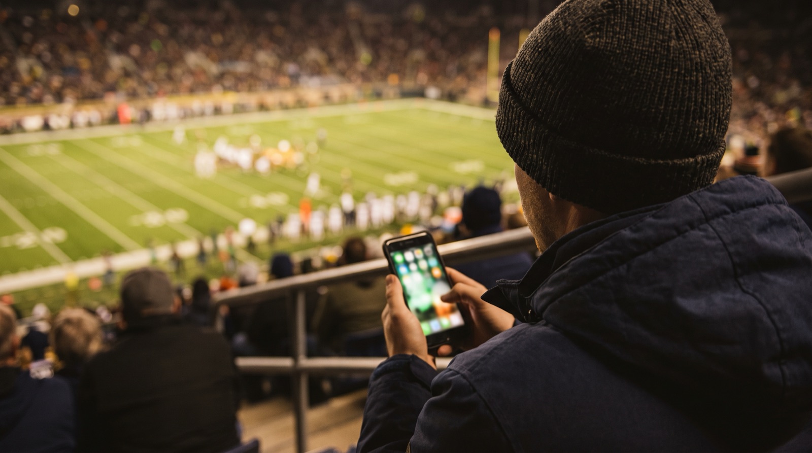 Aficionado consultando su celular durante un partido de futbol americano