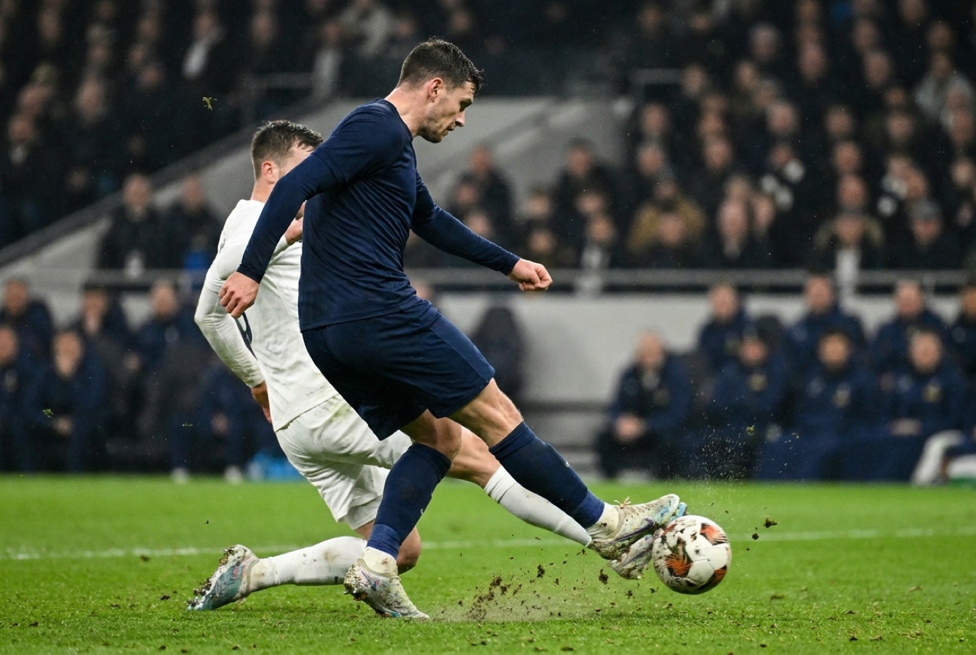 Futbolista rematando el balón en un partido nocturno